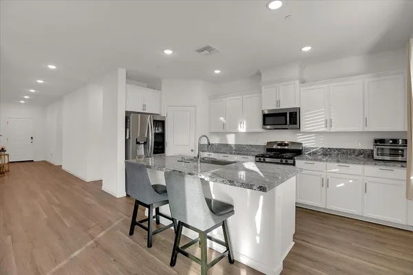 a kitchen with white cabinets stainless steel appliances and dining table