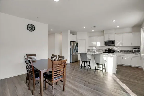 a kitchen with a dining table chairs and wooden floor
