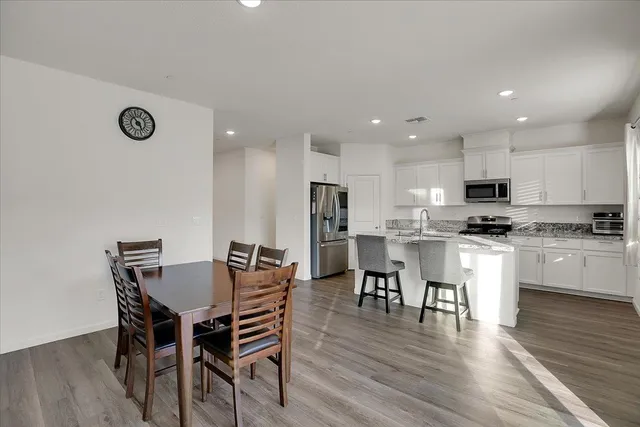 a kitchen with a dining table chairs and wooden floor