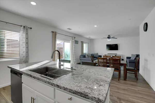 a kitchen with stainless steel appliances granite countertop a sink dishwasher and a stove with wooden floor