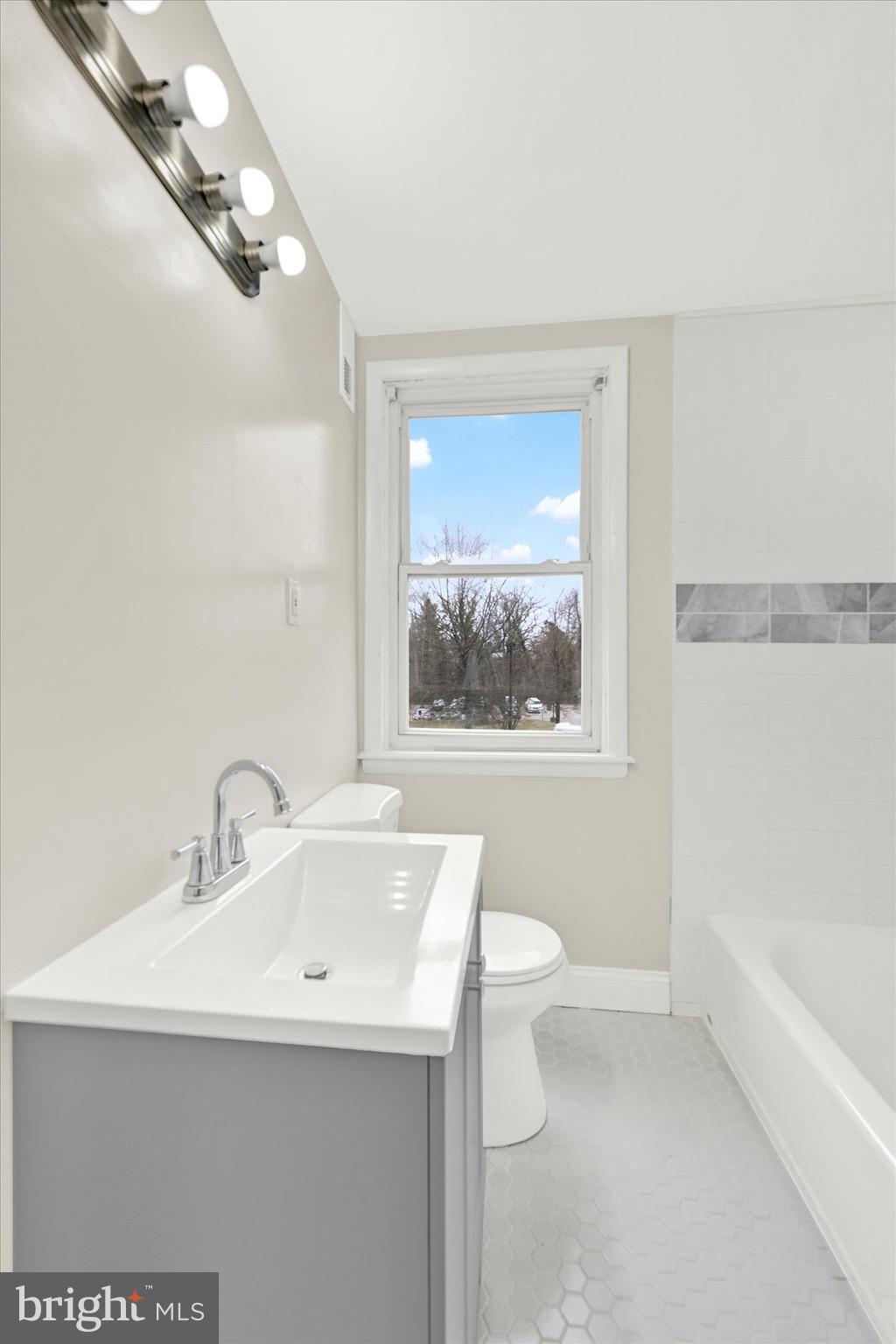 3940 Penhurst Avenue Baltimore, MD 21215 - Photo 13 of 24 a bathroom with a sink a large mirror and a bathtub