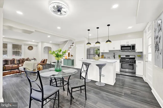 a kitchen with stainless steel appliances kitchen island granite countertop a table chairs and a refrigerator