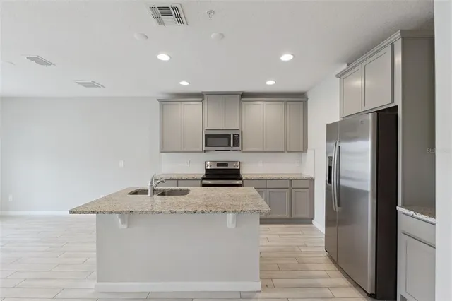 a kitchen with stainless steel appliances granite countertop a refrigerator a stove and a sink