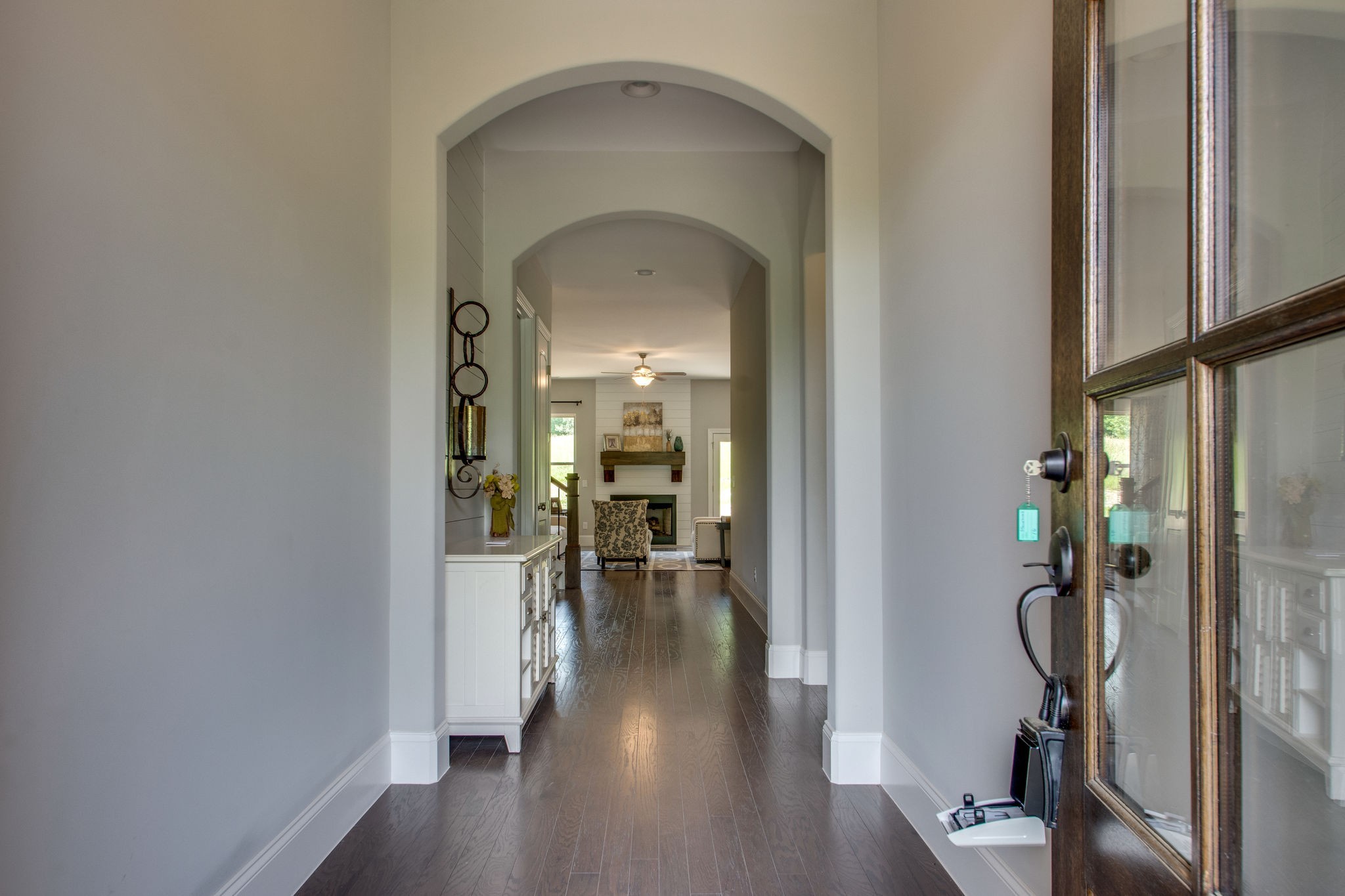 a view of a hallway with wooden floor and a livingroom with furniture