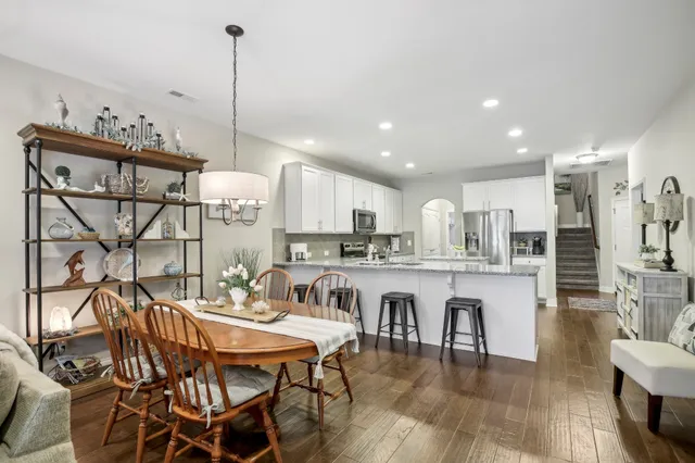 a dining hall with stainless steel appliances kitchen island granite countertop a dining table chairs and granite counter tops