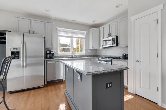 a kitchen with stainless steel appliances granite countertop a sink a stove a refrigerator and cabinets
