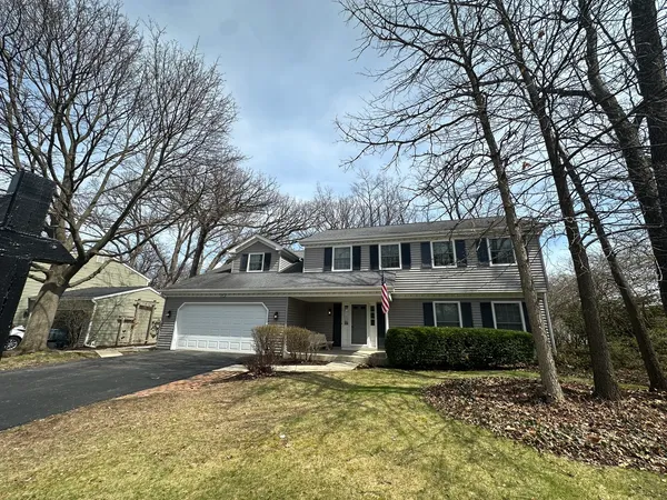 a front view of a house with a yard and large trees