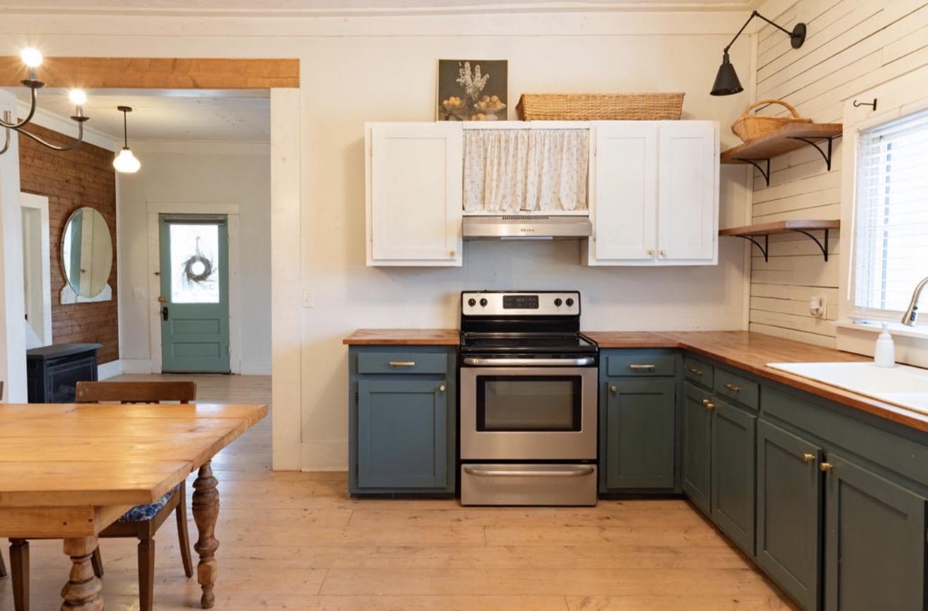 160 Chewalla Road Ramer, TN 38367 - Photo 8 of 39 Dual tone kitchen with stainless steel electric range oven, wood counters, light wood-style floors, two tone cabinetry, and open shelves