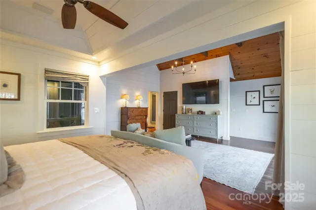 a bedroom with a bed and flat tv screen on the dresser