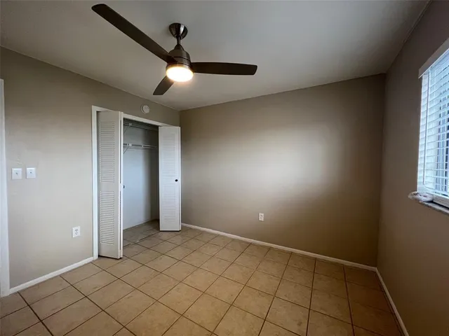 an empty room with windows and fan