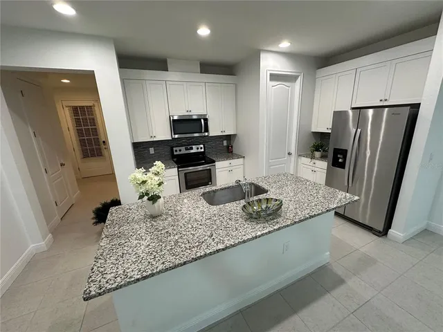a kitchen with granite countertop white cabinets stainless steel appliances and a sink
