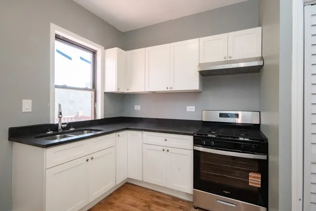 a kitchen with granite countertop white cabinets and black appliances