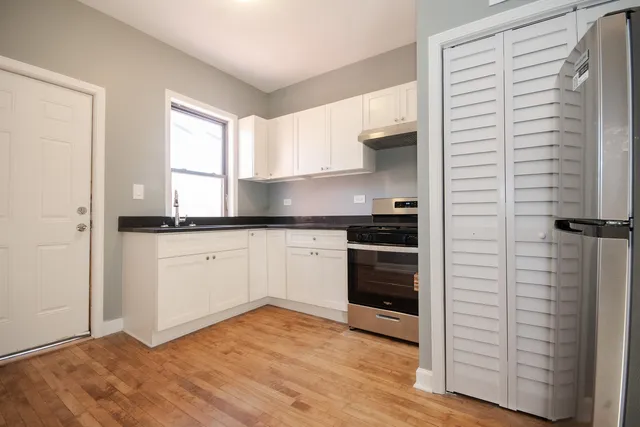 a kitchen with a refrigerator and white cabinets