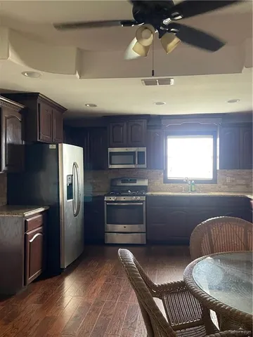 a kitchen with stainless steel appliances granite countertop a refrigerator a stove a sink and a microwave