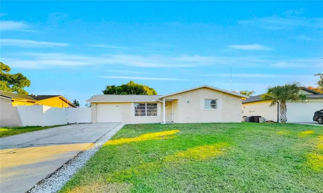 a view of a house with a yard and a large tree