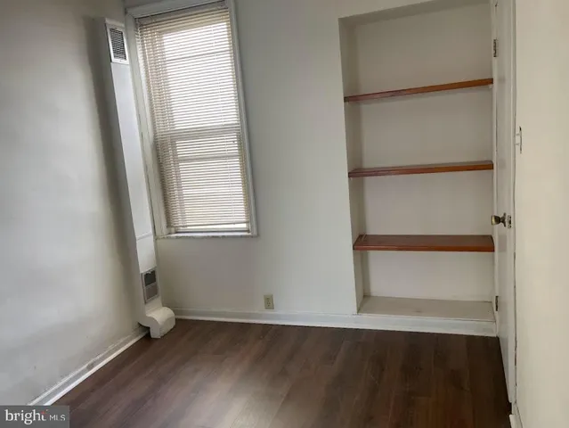 an empty room with wooden floor closet and windows