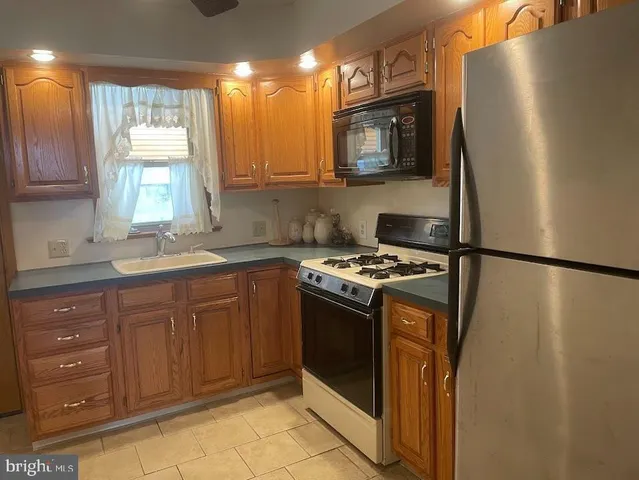 a kitchen with stainless steel appliances granite countertop a refrigerator a sink a stove a microwave and wooden cabinets