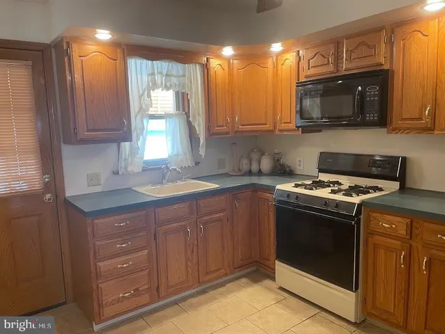 a kitchen with granite countertop a stove top oven sink and cabinets