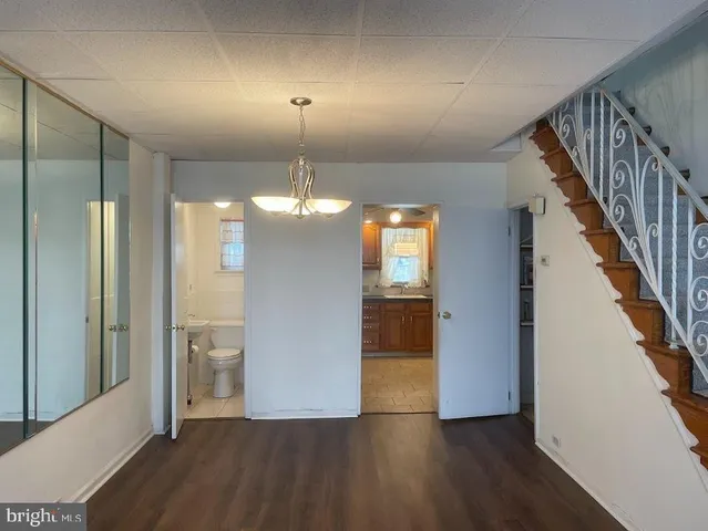 a view of a hallway with wooden floor stairs and a kitchen space