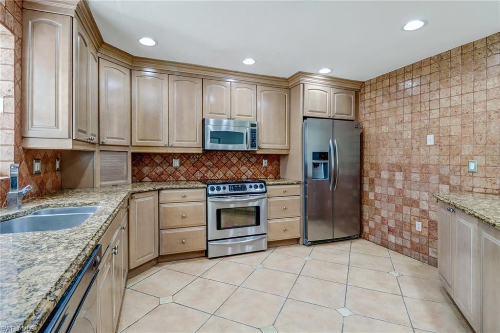 4540 Pine Ridge Road Naples, FL 34119 - Photo 12 of 30 a kitchen with stainless steel appliances granite countertop a stove a refrigerator and a sink
