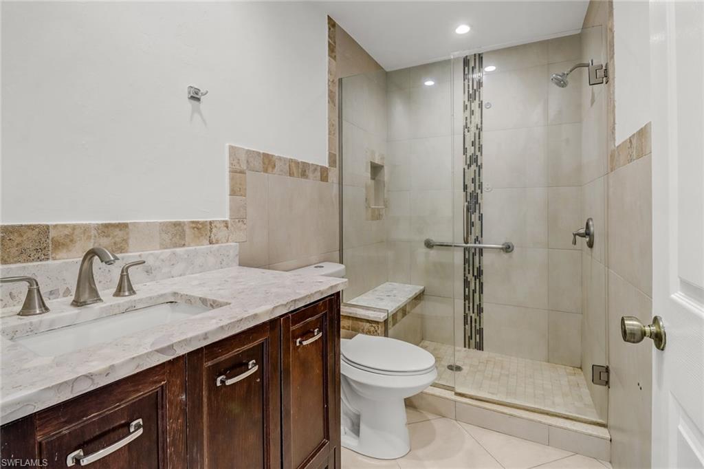 4540 Pine Ridge Road Naples, FL 34119 - Photo 23 of 30 a bathroom with a granite countertop sink a toilet and shower