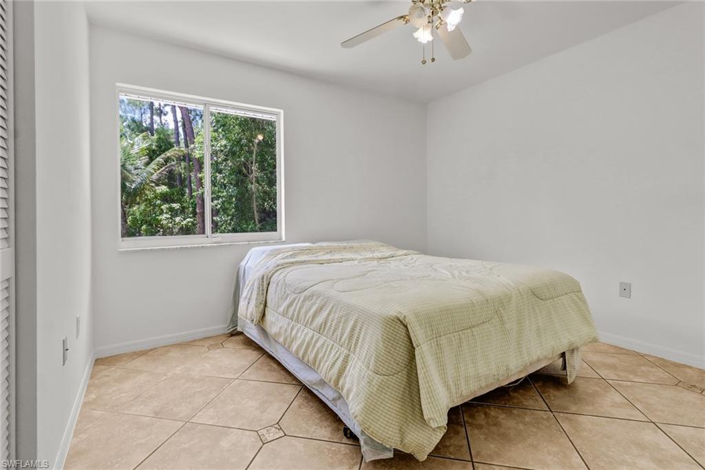 4540 Pine Ridge Road Naples, FL 34119 - Photo 25 of 30 a bed sitting in a bedroom next to a window