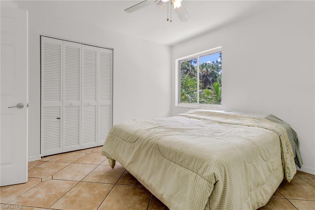 4540 Pine Ridge Road Naples, FL 34119 - Photo 26 of 30 a large bed sitting in a bedroom next to a window and a chandelier
