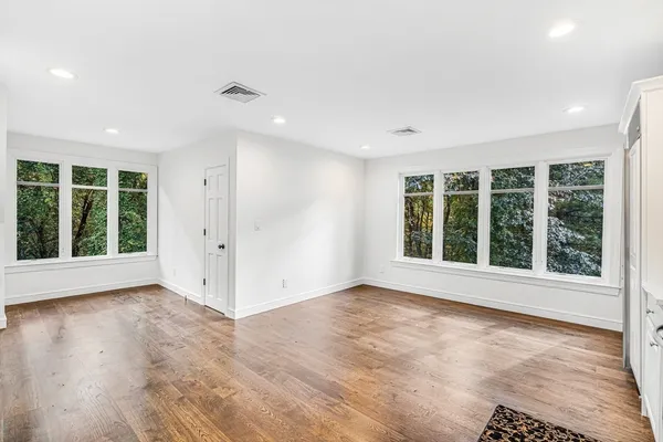 a view of an empty room with a window and wooden floor