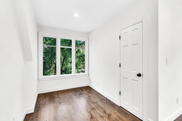 an empty room with wooden floor and windows