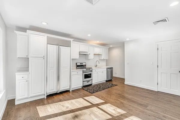 a kitchen with stainless steel appliances a refrigerator and white cabinets