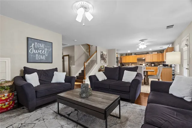 a living room with furniture kitchen view and a chandelier