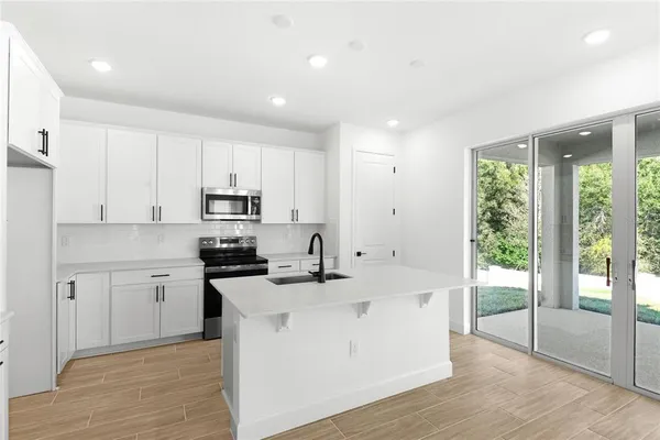 a kitchen with a sink a stove a refrigerator and white cabinets