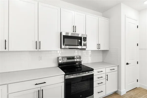 a kitchen with granite countertop white cabinets and black appliances