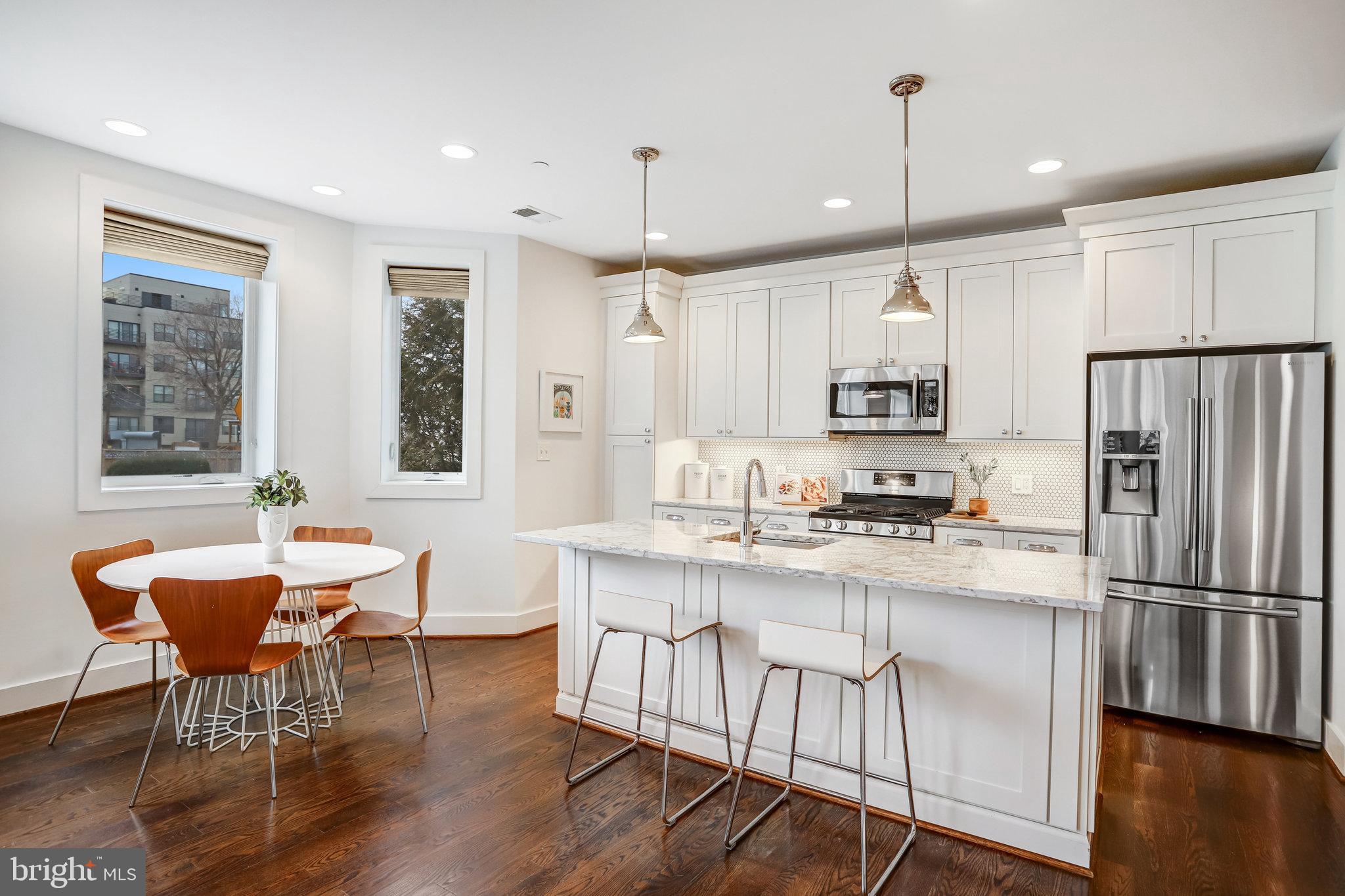 1200 Staples Street Northeast, Unit 1 Washington, DC 20002 - Photo 11 of 37 a kitchen with stainless steel appliances granite countertop a dining table chairs refrigerator and sink