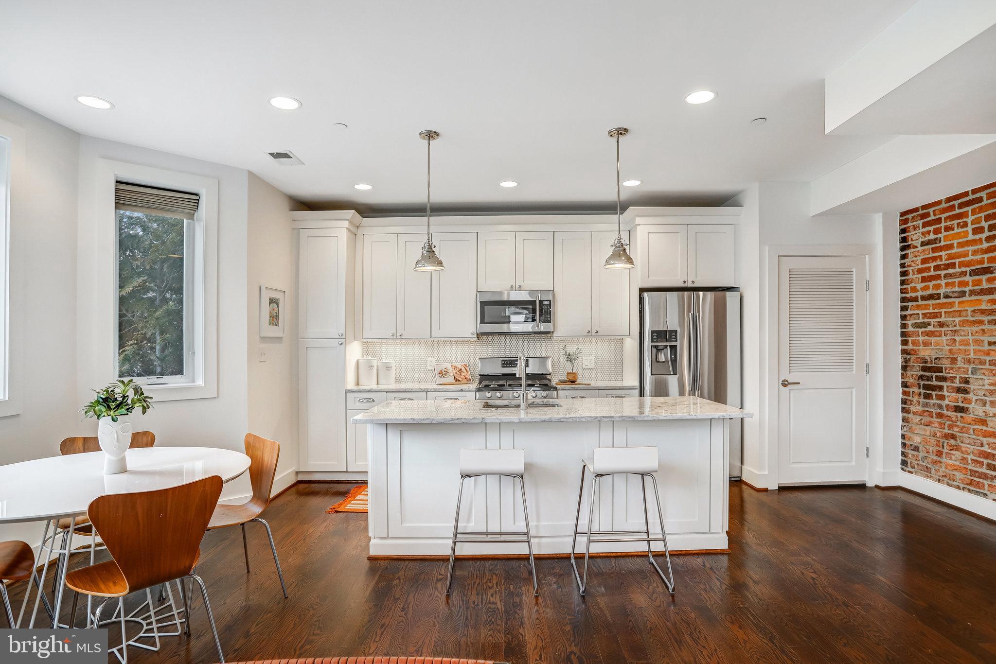 1200 Staples Street Northeast, Unit 1 Washington, DC 20002 - Photo 12 of 37 a kitchen with stainless steel appliances granite countertop a dining table chairs stove refrigerator and cabinets