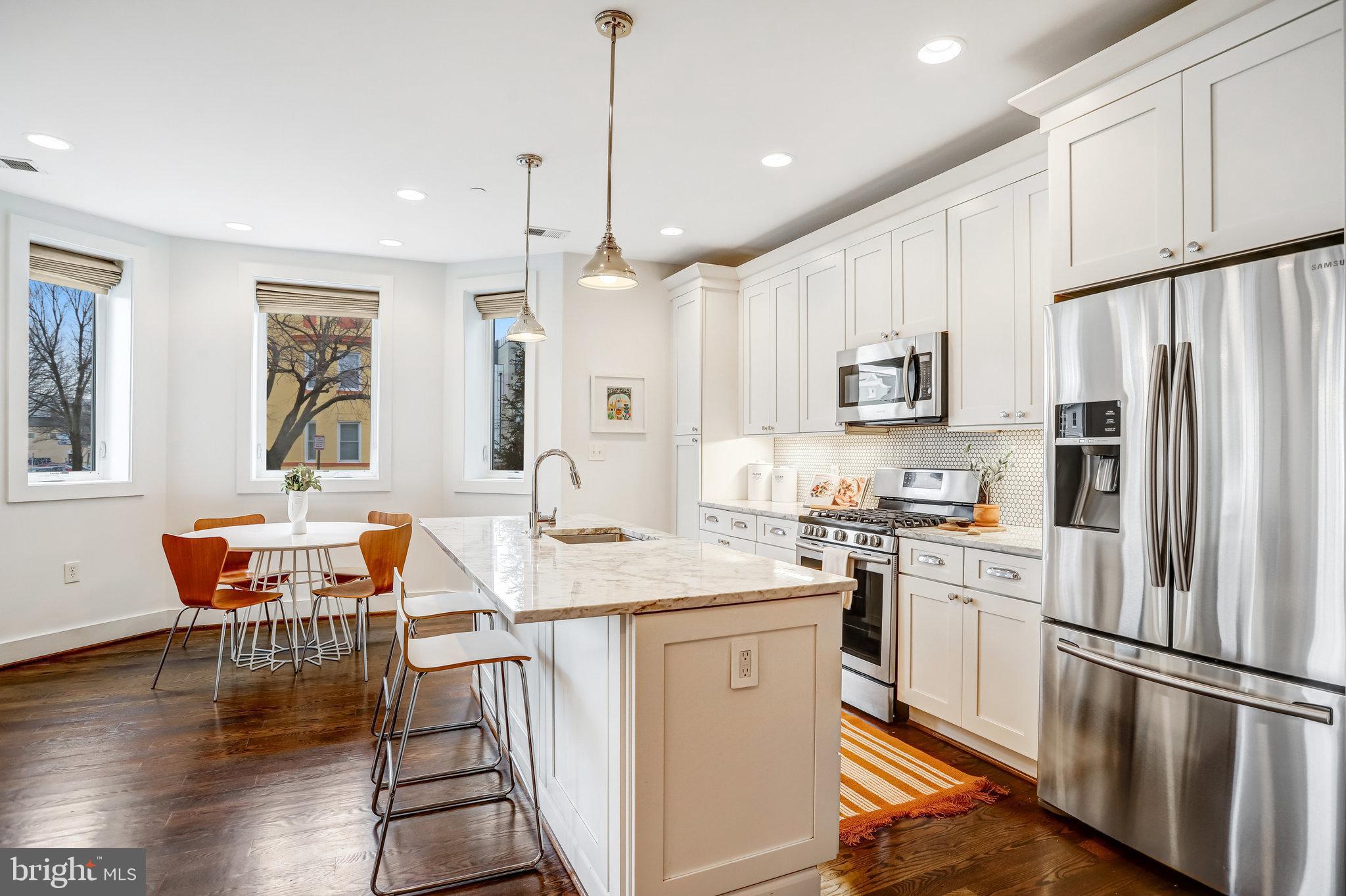 1200 Staples Street Northeast, Unit 1 Washington, DC 20002 - Photo 13 of 37 a kitchen with stainless steel appliances granite countertop a refrigerator a stove a sink a dining table and chairs with wooden floor