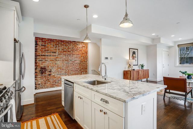 a kitchen with granite countertop kitchen island stainless steel appliances a sink and cabinets