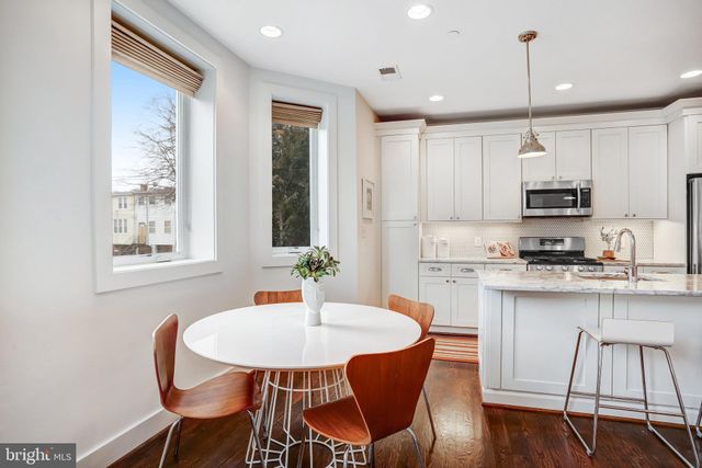 a kitchen with kitchen island a dining table chairs and white cabinets