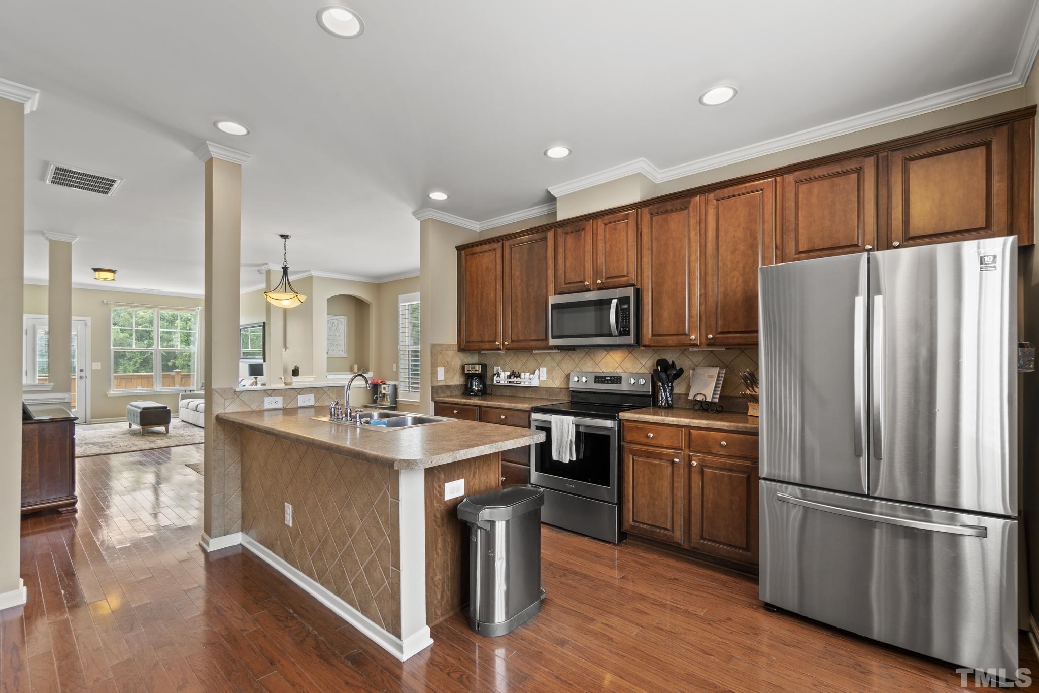 2956 Casona Way Raleigh, NC 27616 - Photo 11 of 27 a kitchen with kitchen island granite countertop stainless steel appliances a sink a stove a refrigerator cabinets and wooden floor