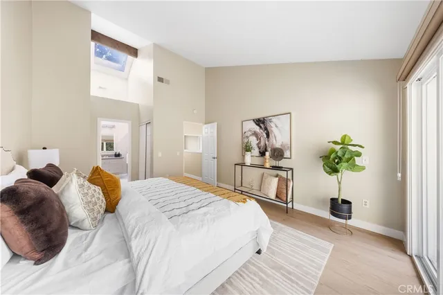 a bedroom with a large bed a potted plant and a window