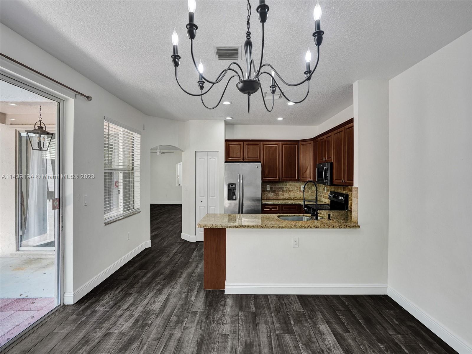 4185 Tree Top Road Cooper City, FL 33026 - Photo 12 of 36 a kitchen with stainless steel appliances granite countertop a refrigerator a stove and a wooden floors