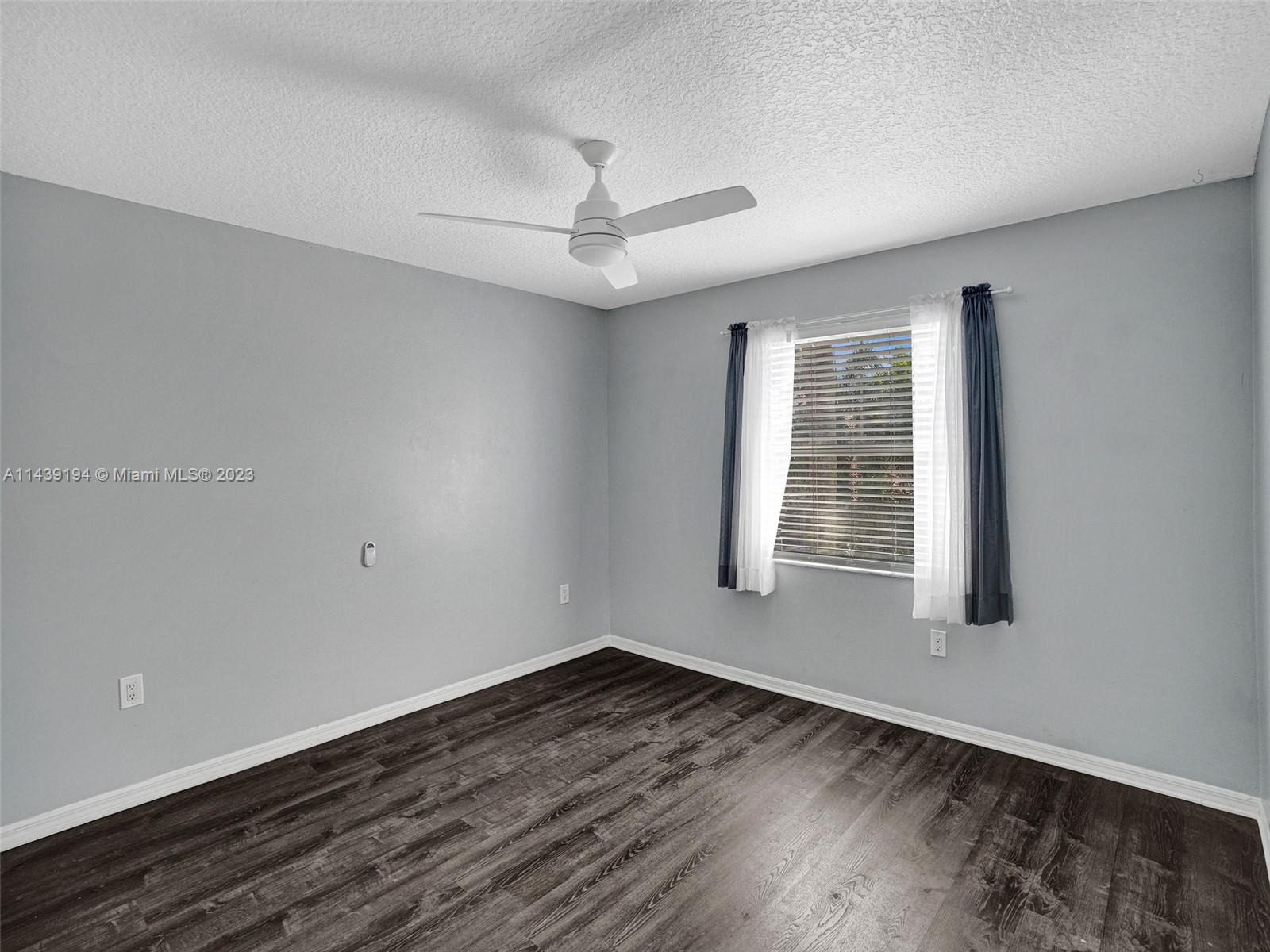 4185 Tree Top Road Cooper City, FL 33026 - Photo 21 of 36 an empty room with wooden floor and windows