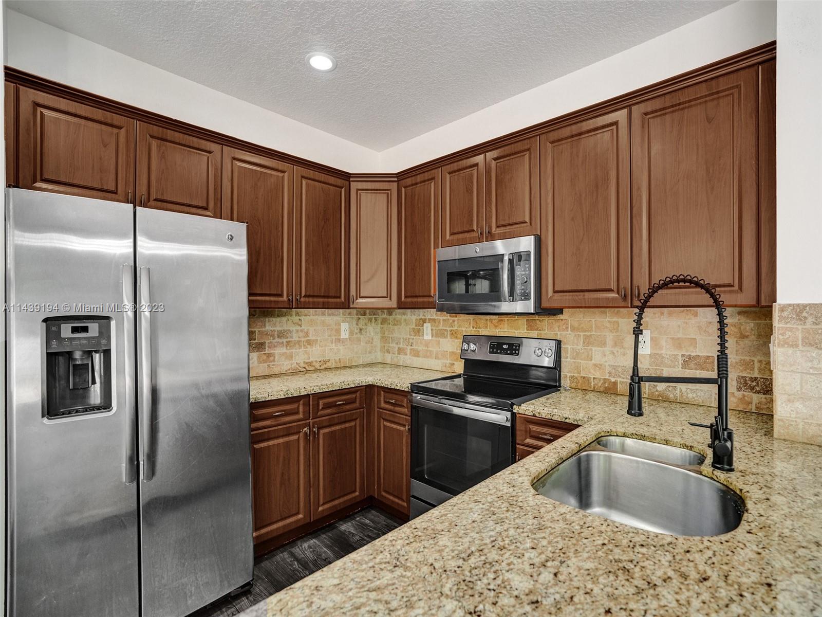 4185 Tree Top Road Cooper City, FL 33026 - Photo 10 of 36 a kitchen with stainless steel appliances granite countertop a refrigerator sink and microwave