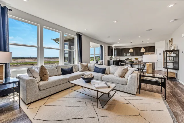 a living room with furniture wooden floor and a large window