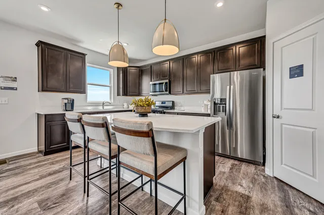 a kitchen with stainless steel appliances granite countertop a refrigerator a stove a sink dishwasher a dining table and chairs with wooden floor