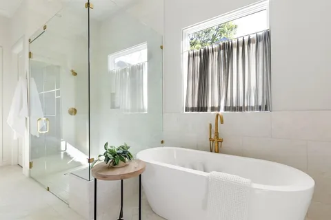a white bath tub sitting in a bathroom next to a window