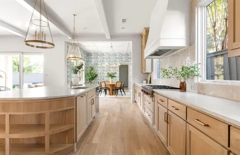 a large kitchen with kitchen island a large window a sink and stainless steel appliances