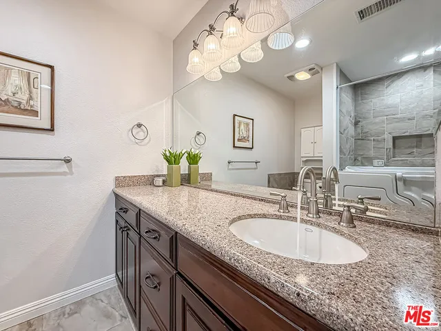 a bathroom with a granite countertop tub sink and mirror