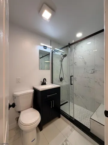 a bathroom with a toilet sink vanity granite and shower