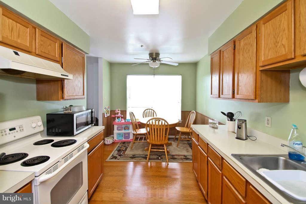 4739 Ridgeline Terrace, Unit 301 Bowie, MD 20720 - Photo 10 of 25 a kitchen with a stove a sink a dining table and chairs